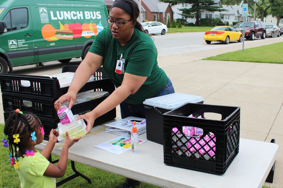 AmeriCorps intern distributes a fresh meal from the Lunch Bus to a child in south suburban Lansing, Ill.