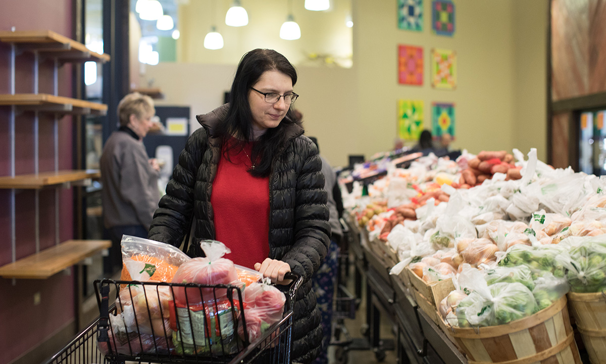 Person with shopping cart selects produce at Willow Creek Food Pantry