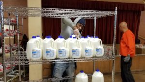 A volunteer lines up milk at a distribution at the Emergency Food Pantry at St. Ailbe in Calumet Heights.