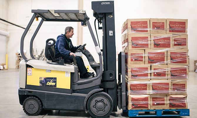 A forklift operator moves boxes of produce in the Food Depository warehosue