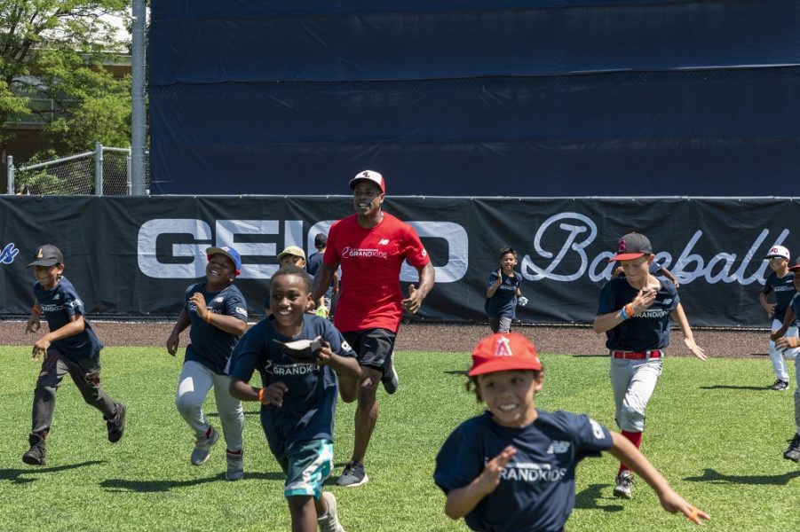 Curtis Granderson runs with children at his baseball camp.