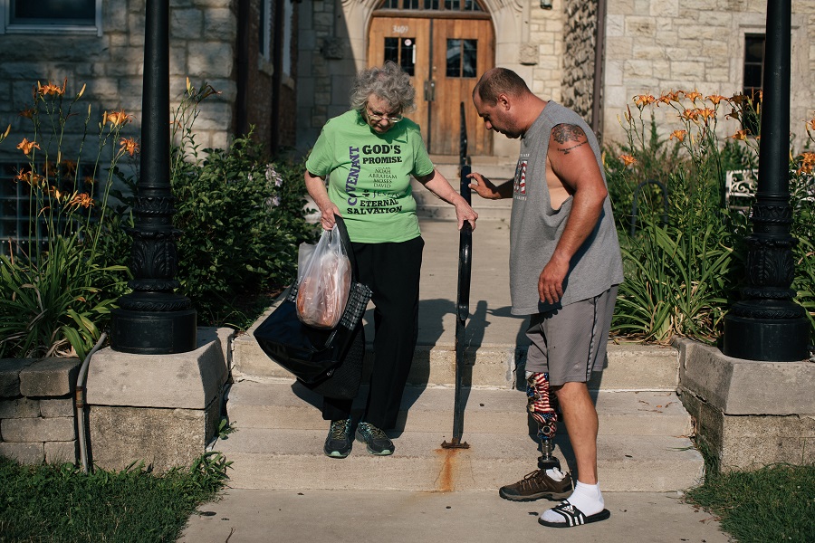 Joe Cannella helps his mother down the stairs in front of the food pantry.