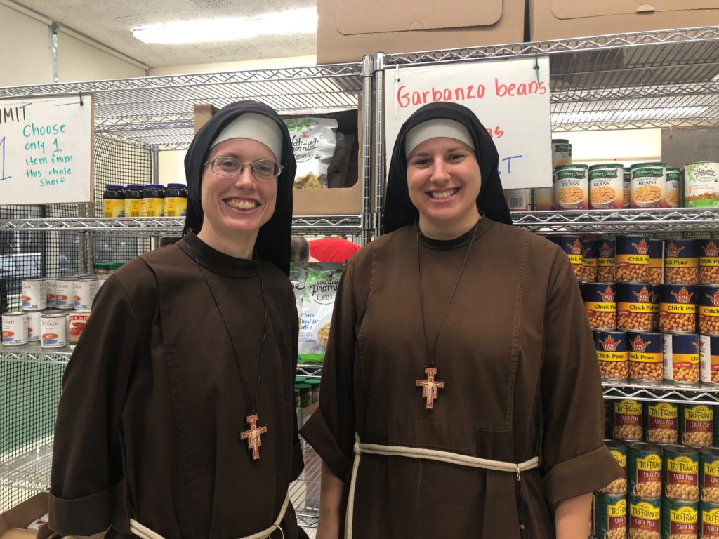 Sisters Stephanie Baliga and Laura Toth pose together inside the Mission of Our Lady of the Angels food pantry