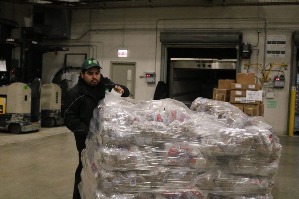 Food Depository truck helper Steve Castro wraps a pallet of potatoes before it goes onto a distribution truck. The potatoes were some of the Thanksgiving food delivered as part of the Food Depository's holiday distributions.