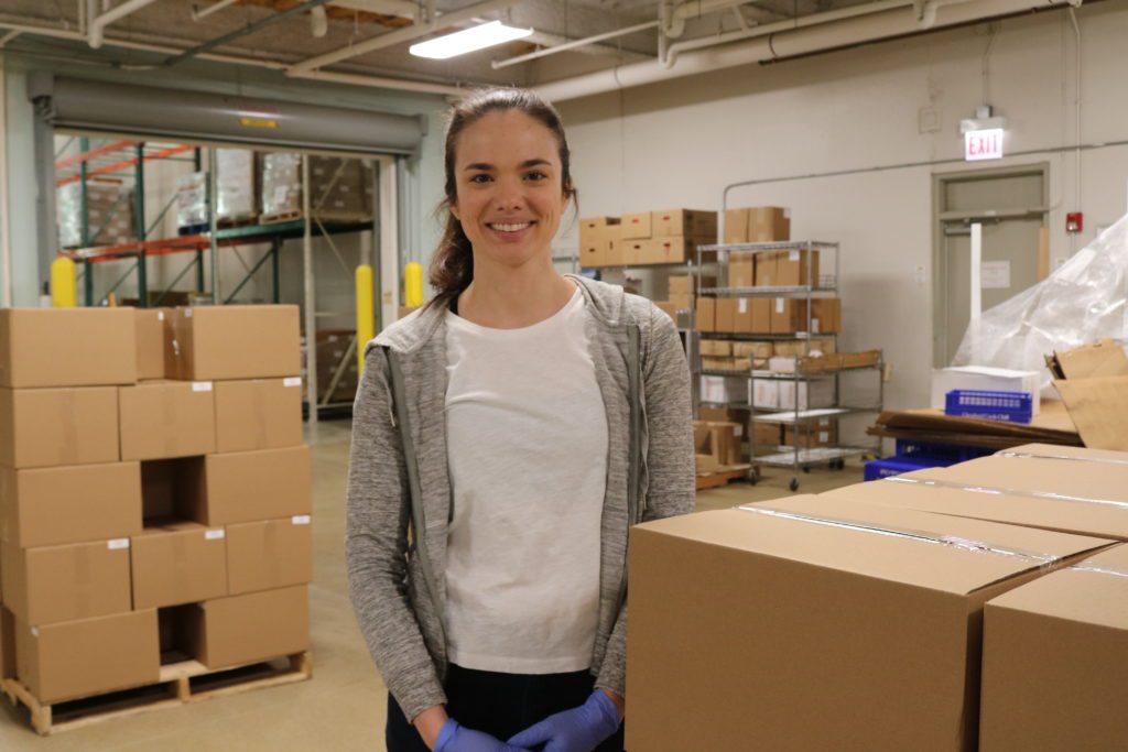 Caroline Boneham poses for a photo next to food boxes in the Greater Chicago Food Depository warehouse