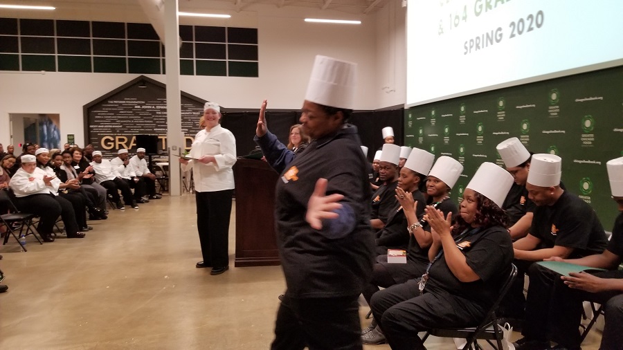 A Chicago's Community Kitchens graduate walks up to receive her certificate