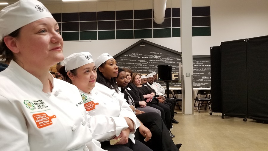 The Chicago’s Community Kitchens team listens to a student speaker at graduation.