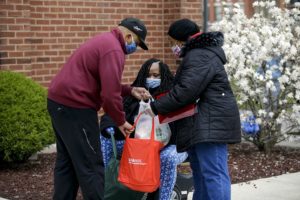 Volunteer Franklin Cosey-Gay and Pastor Sandra Gillespie help affix bags of food to Dorene Couch's wheelchair.