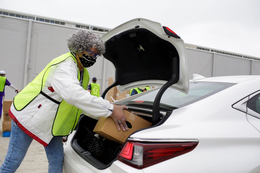 A volunteer at the Trinity United Church of Christ fills a car trunk with food