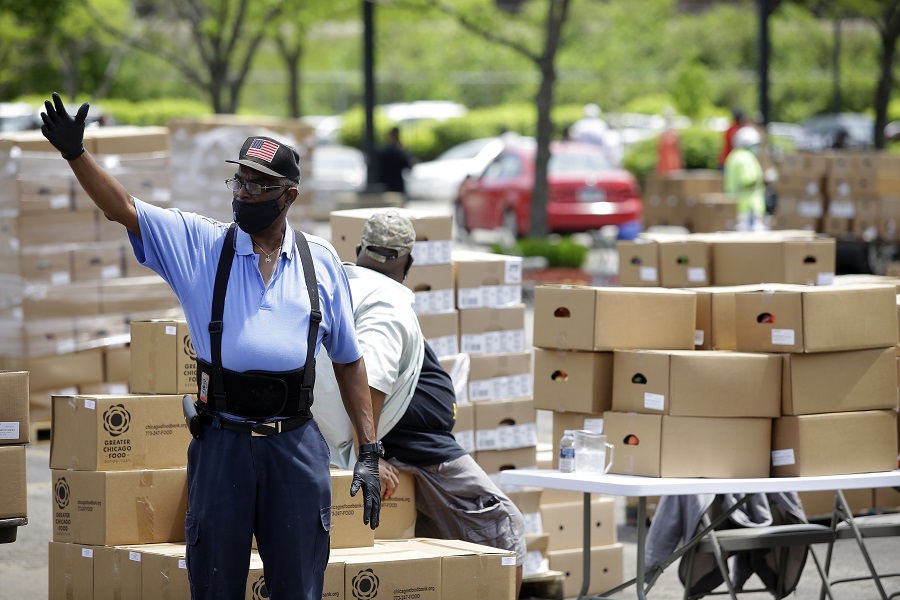 A volunteer at the Apostolic Church of God in Woodlawn – one of more than 100 volunteers who help each week – gestures for cars to move forward during the weekly food pop-up. 