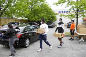 Young men volunteering in Auburn Gresham carry boxes of fresh produce, meat and nonperishable food to a car.