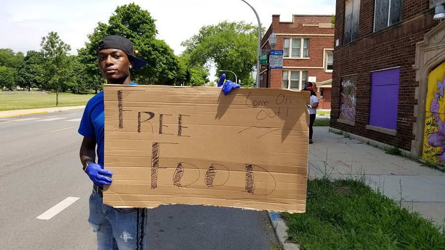A volunteer with Teamwork Englewood tries to get the attention of passersby on Racine Avenue.