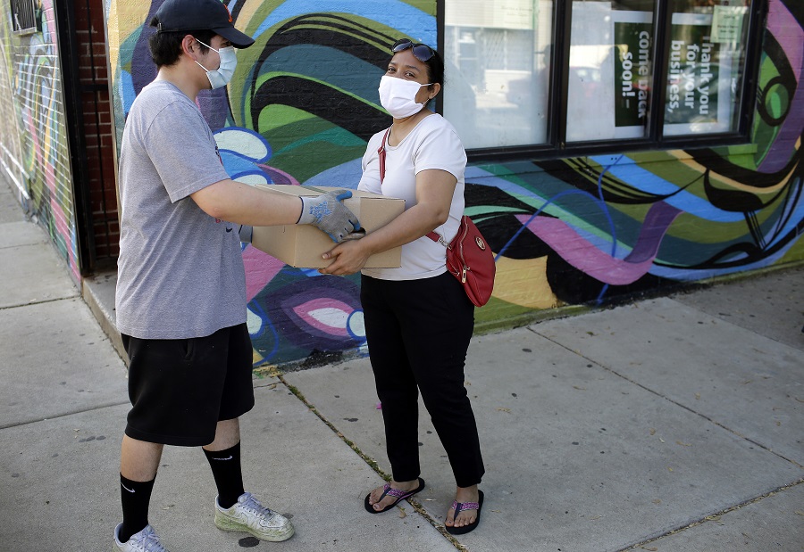 A volunteer hands a neighbor a box of food at New Life Centers of Chicagoland, a new partner of the Food Depository.