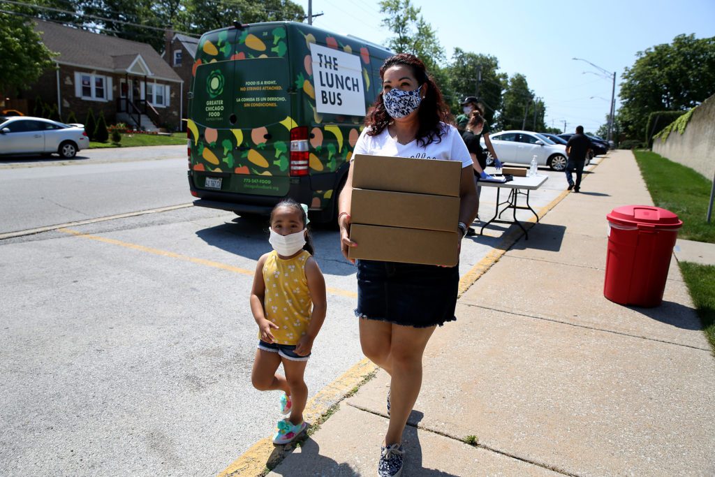 A mother and daughter leave with several days worth of meals from the Lunch Bus stop in Lansing