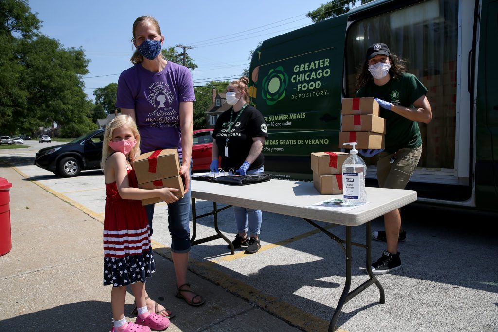 A mother and her daughter pick up meals at the Lansing Lunch Bus stop