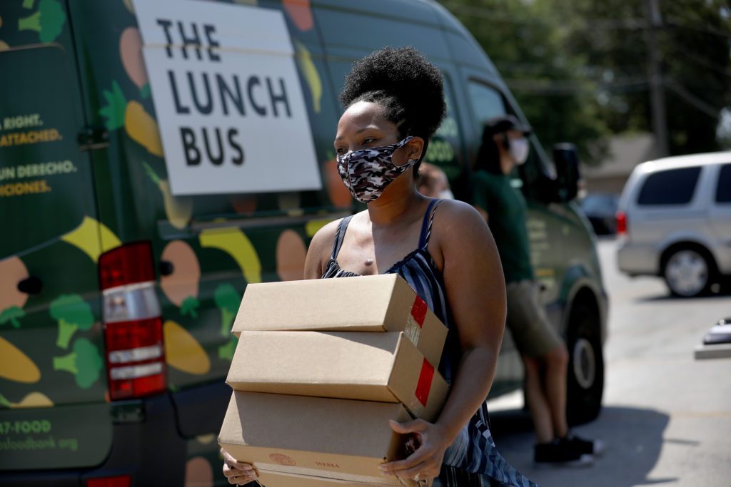 A guest picks up meals at the Lansing Lunch Bus