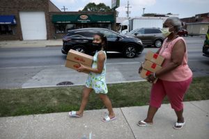 A girl and her grandmother walk to their car in Berwyn after receiving food from the Lunch Bus