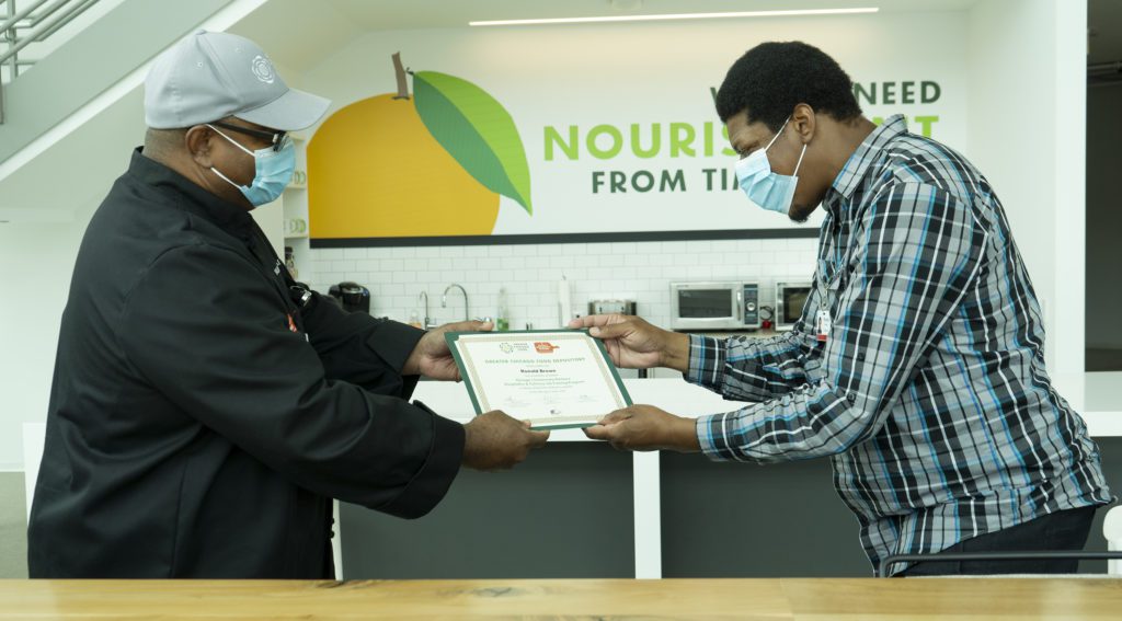 Ronald Brown (right) receives his graduation certification from Malik Kemokai, the Food Depository's director of workforce development.strategy and operations.
