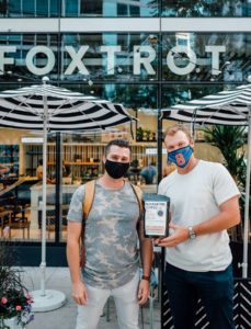 Caleb Benoit of Connect Roasters, at left, and Ian Happ pose for a portrait with Quarantine Coffee in front of a Foxtrot location. (Photo credit: Ellen Ternes for Foxtrot)