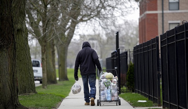 A man walks down the street after receiving food from a food pantry.
