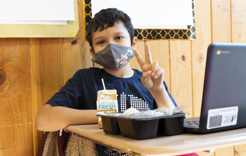 A child at the Barreto Club poses for a photo while eating his lunch