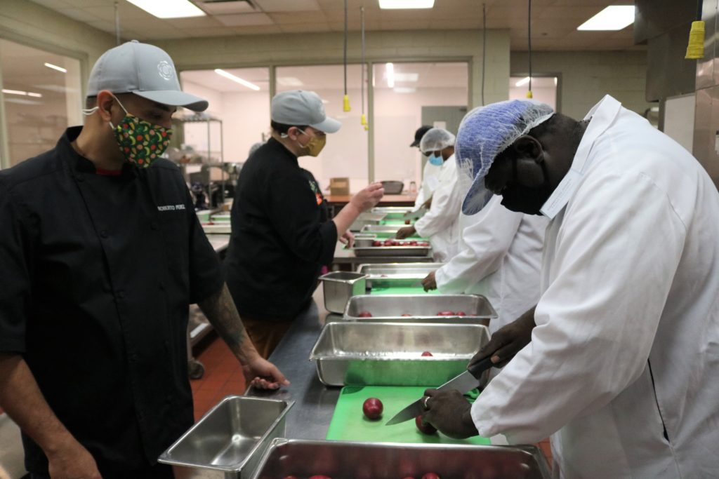 Compton Jones (right) takes instruction from chef instructor Roberto Perez during a knife cuts lesson