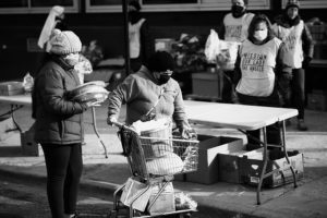 A family leaves a holiday food distribution with a turkey, pies and other holiday food.