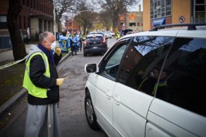 Bishop Bob Lombardo directs a car in to the holiday food distribution.