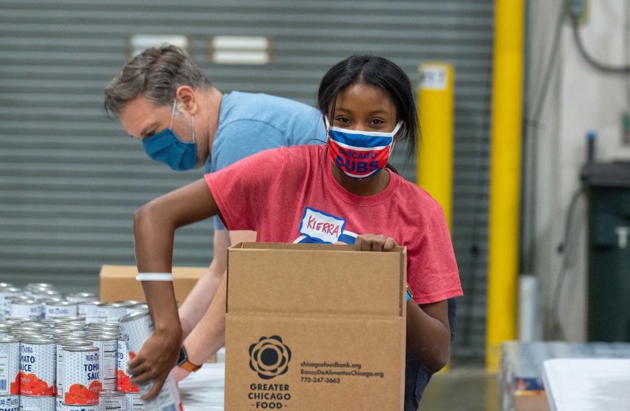 A volunteer with Cubs Charities packs boxes of emergency food for families in need.