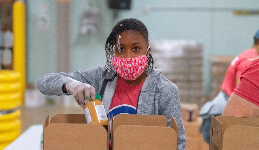 A young Cubs Charities volunteer adds a jar of peanut butter to an emergency food box at the MLK Day of Service.