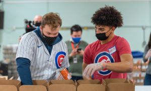 Cubs outfielder Ian Happ, left, talks to Abel Yolich, of Humboldt Park, as they pack food boxes.