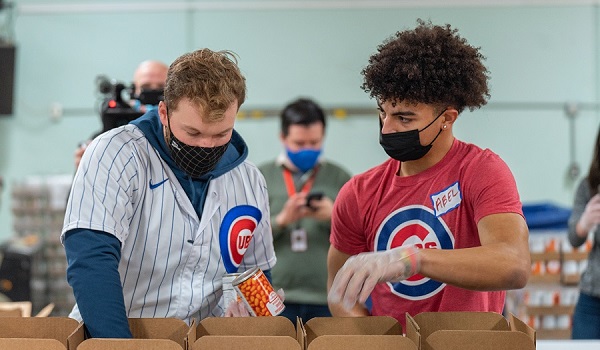 Cubs outfielder Ian Happ, left, talks to Abel Yolich, of Humboldt Park, as they pack food boxes.