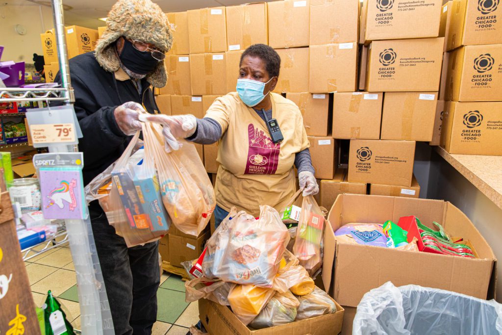 Charles White (left) organizes his groceries after going through the Sheldon Heights food pantry