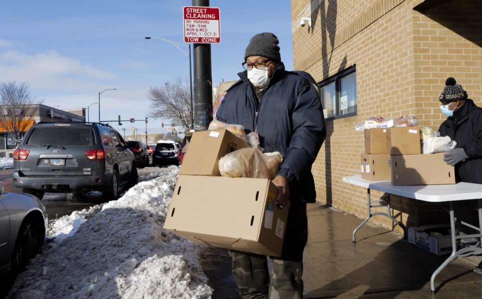 Un cliente en la despensa de la Iglesia Evangelica Emanuel recibe caja de alimentos.