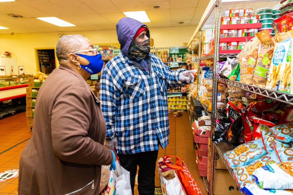 A Sheldon Heights food pantry volunteer helps guest Nathan Crosby select groceries.
