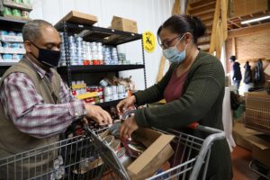 A Blue Cap volunteer loads food into a woman's cart.