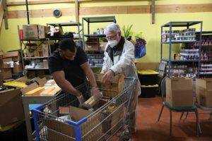 Blue Cap volunteer Mark Williams helps a pantry guest.