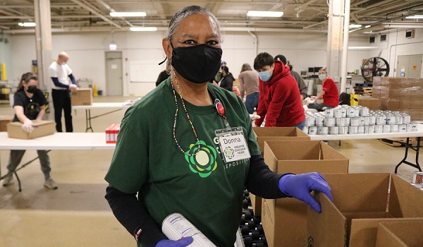 Donna Mitchell, a Food Depository volunteer, helps pack emergency food boxes.