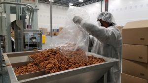 A CREDMADE worker loads a large batch of pretzels into the packing machine.