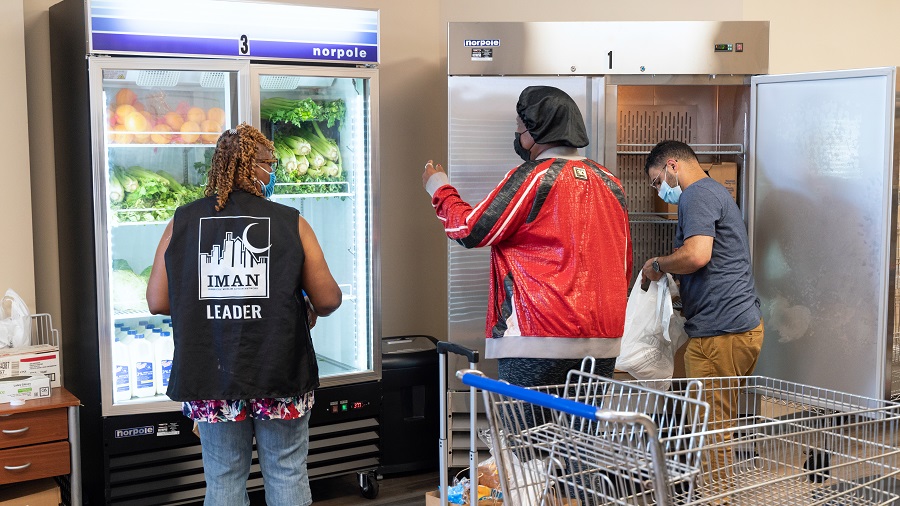 Staff at the IMAN Food and Wellness Center bag produce and meat for a pantry guest.