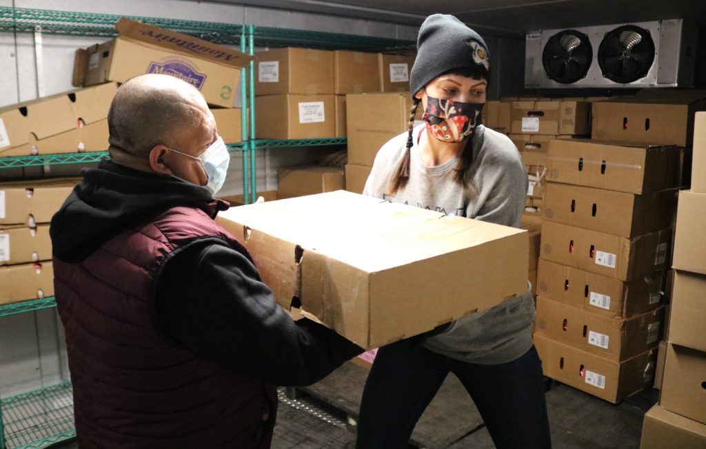 Volunteers Stephanie Seacord and Israel Ramos stock the Mission of Our Lady of the Angels' pantry freezer with meat for its holiday food distribution