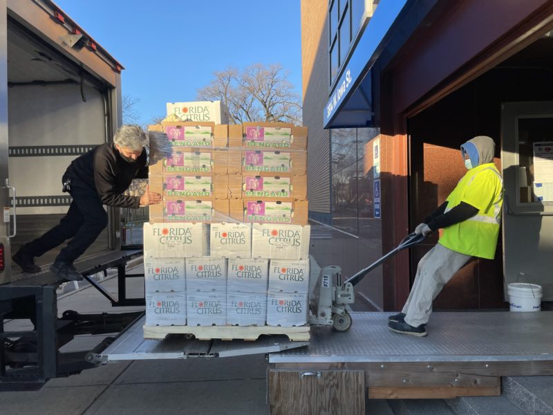 Food Depository driver Efrain Reyes and volunteer Gregory Williams move a delivery of fresh produce into the Mission of Our Lady of the Angels food pantry ahead of its holiday distribution.