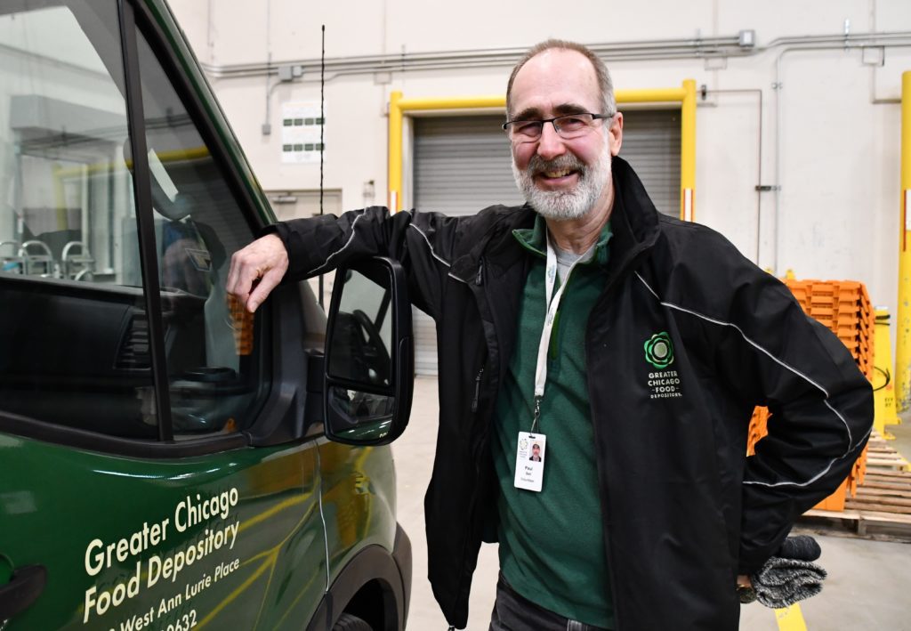 Paul Dell poses for a photo next to a Food Depository truck