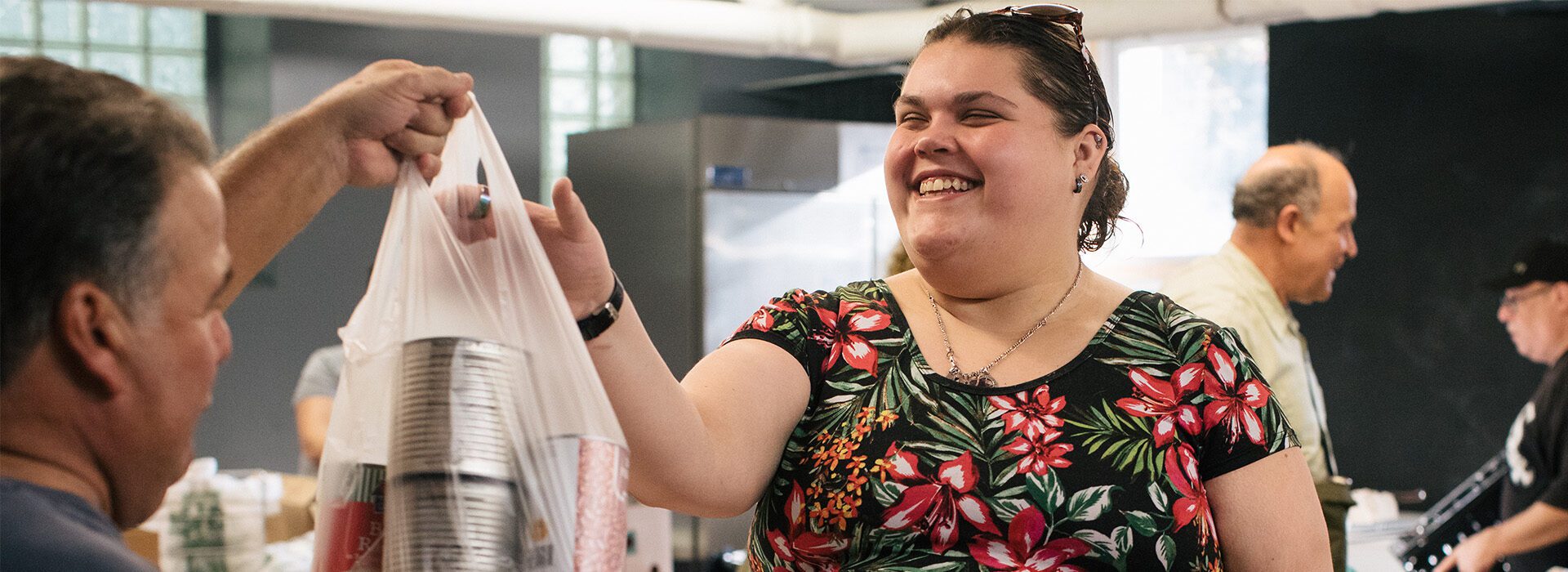 Smiling woman receiving groceries at a food pantry.