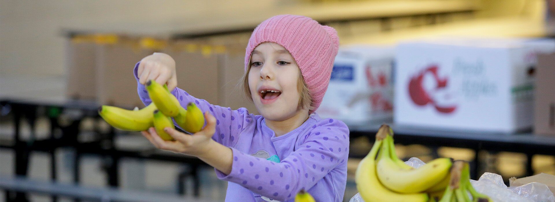 Girl smiles while receiving bananas