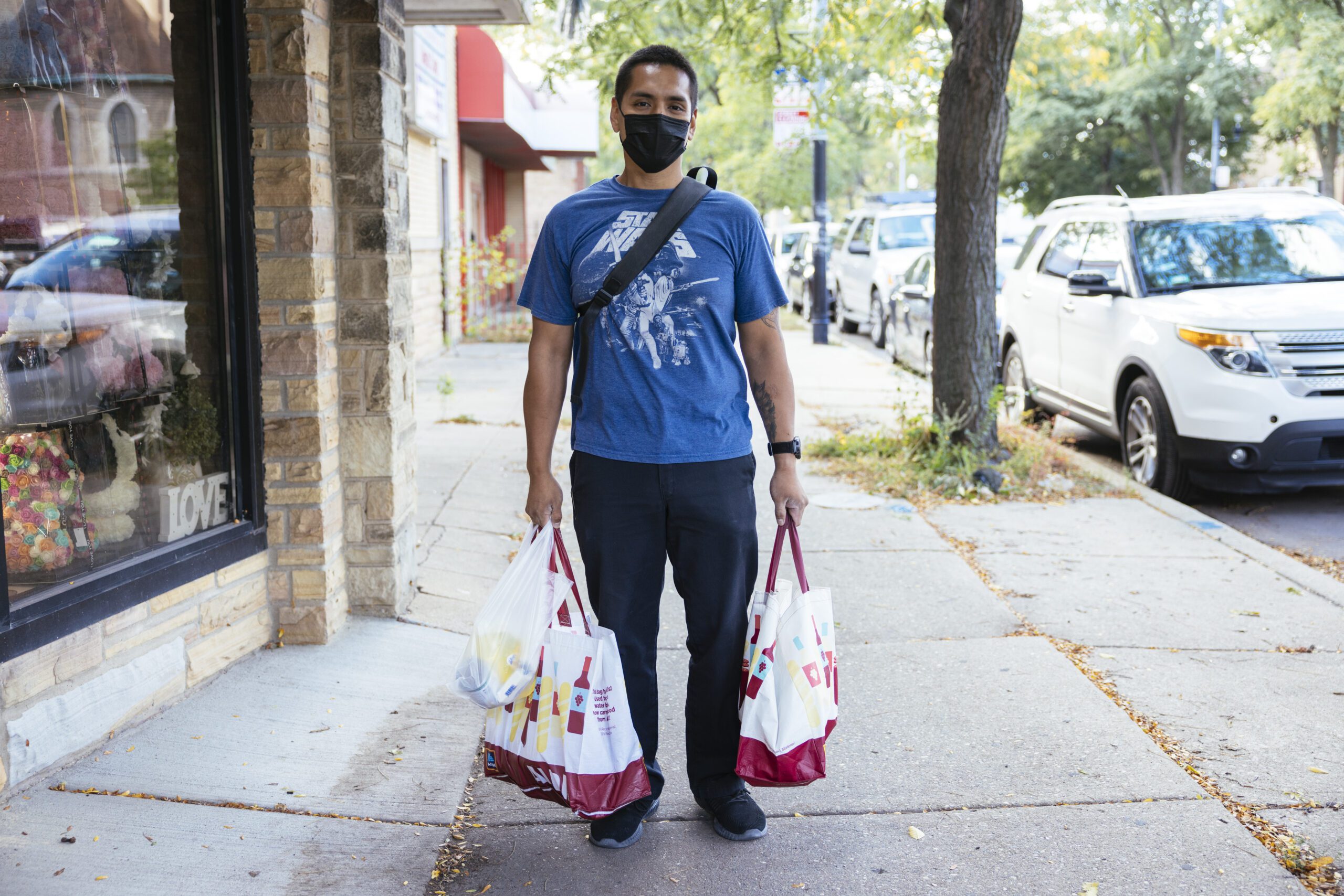 A man carrying groceries wearing a face mask
