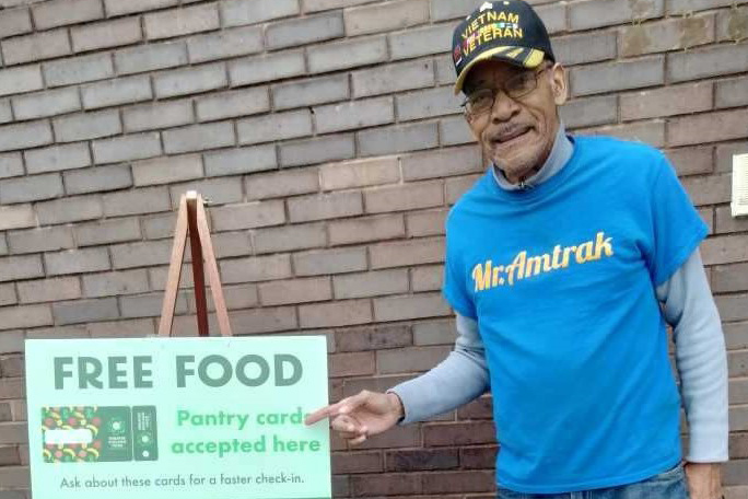 a volunteer points to a sign outside a food pantry