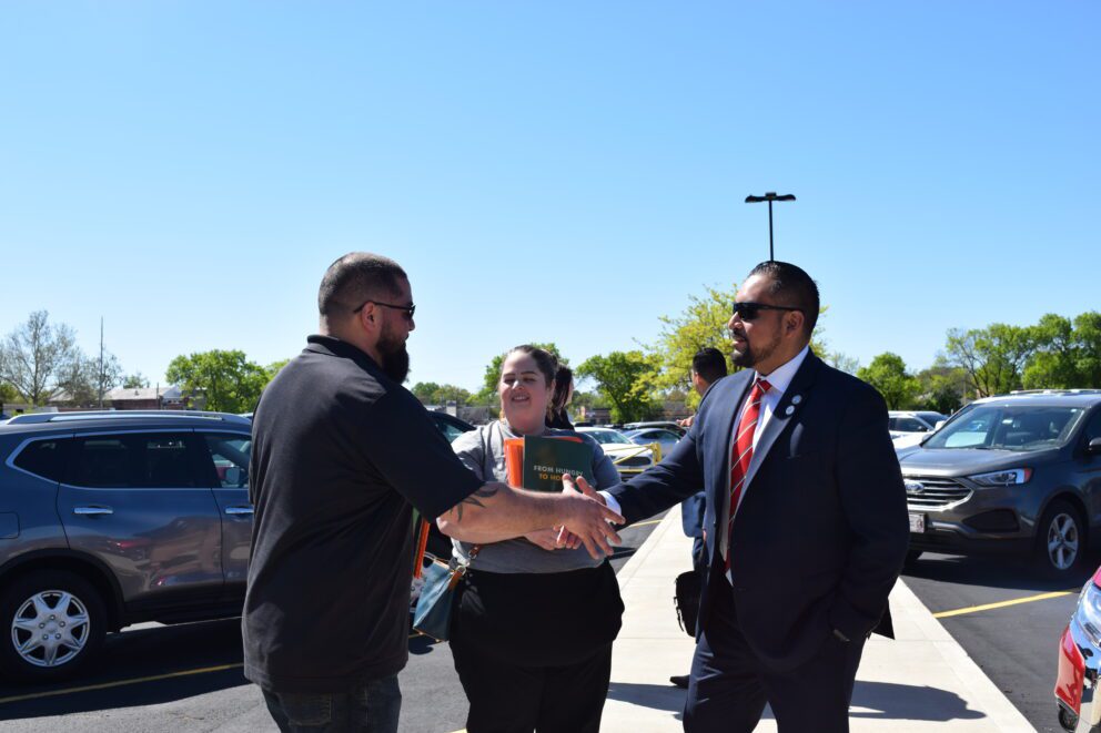 two men shake hands as a woman watches