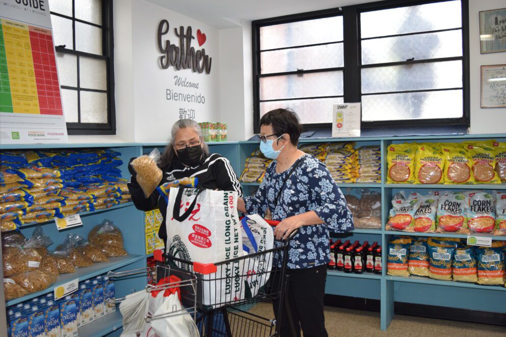 a woman shops at a food pantry with the help of another woman