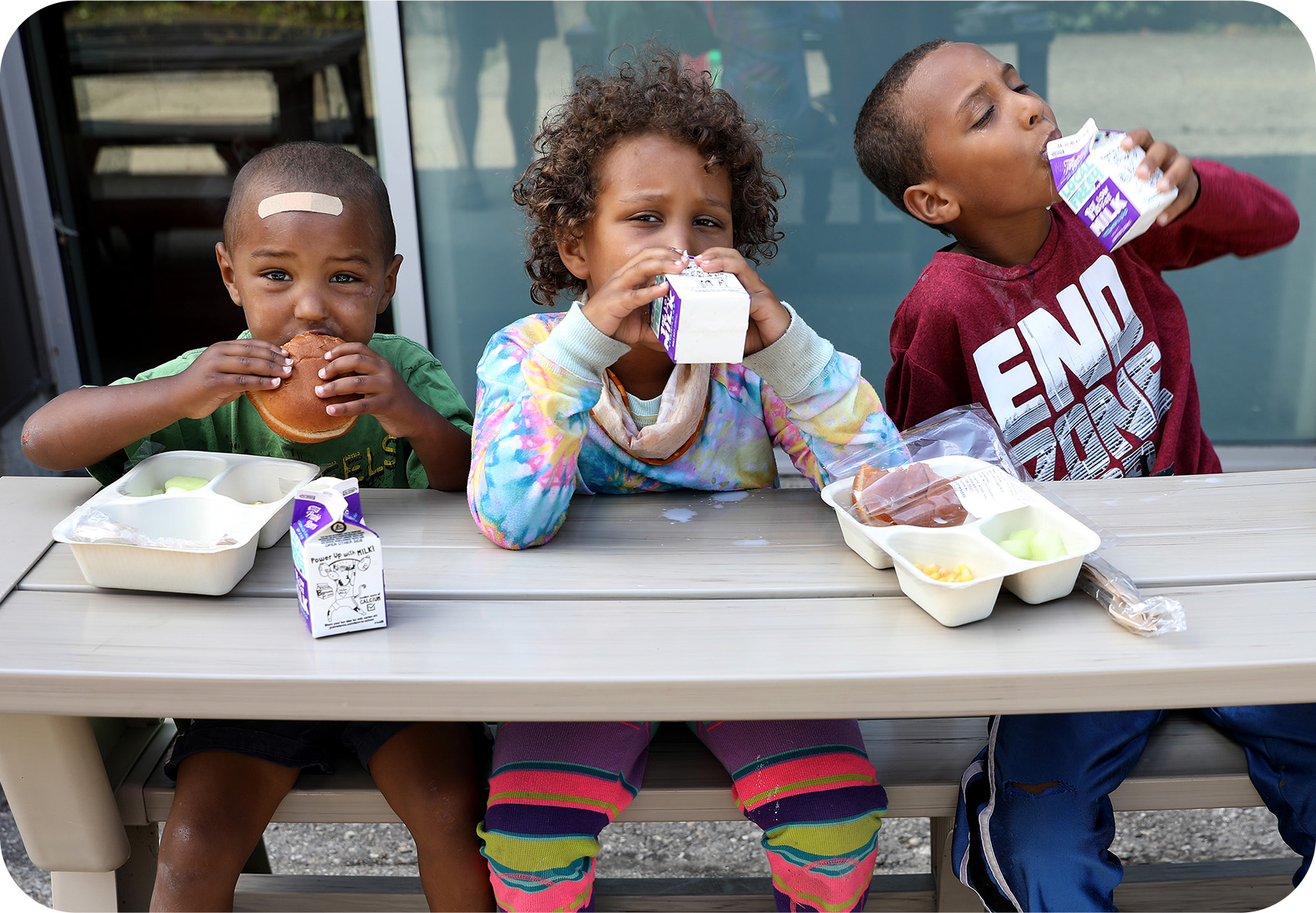 3 children are eating a healthy lunch all because of the Lunch Bus.